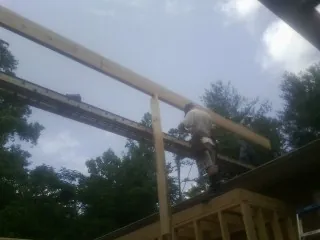 Carpenter setting a ridge beam over a new addition frame — Ice Dam Removal by Roofing Brothers in Bybee