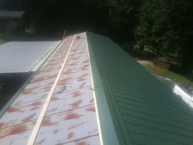 Old rusted panels beside newly installed green metal roofing — Wind Damage Roof Repair by Roofing Brothers in Bybee