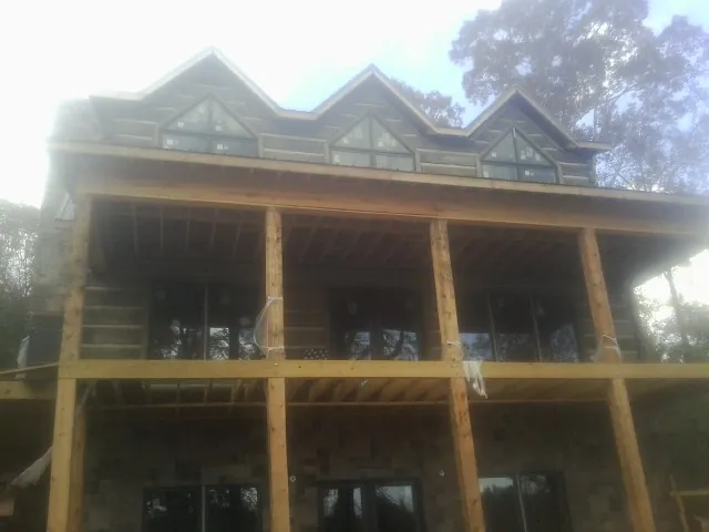 Dormers and porch framing on a large log home under construction — Roof Coating work by our crew in Bybee