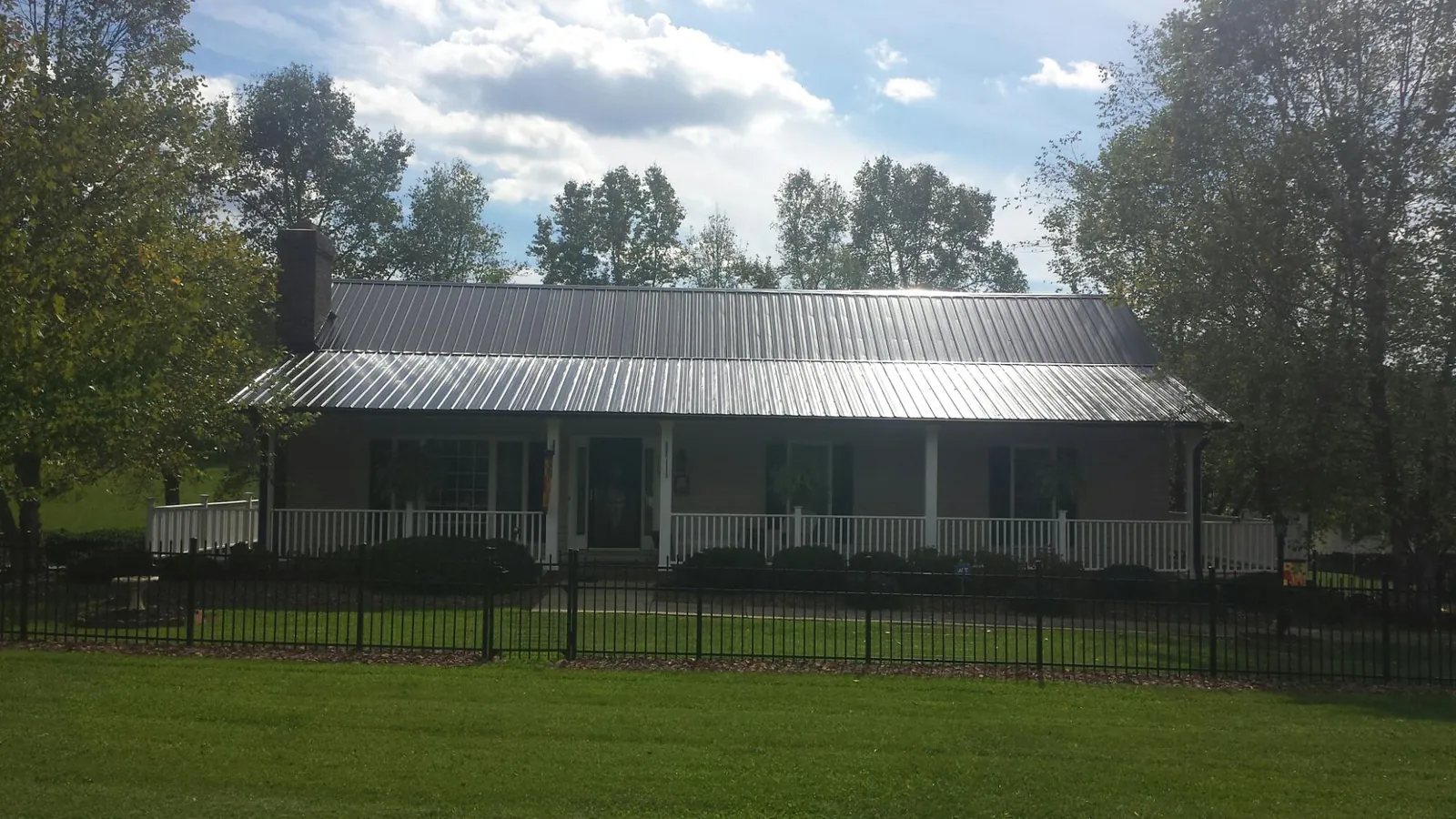 Gray metal roof on a brick ranch with a full width front porch — Gutter Guard Installation work by our crew in Bybee