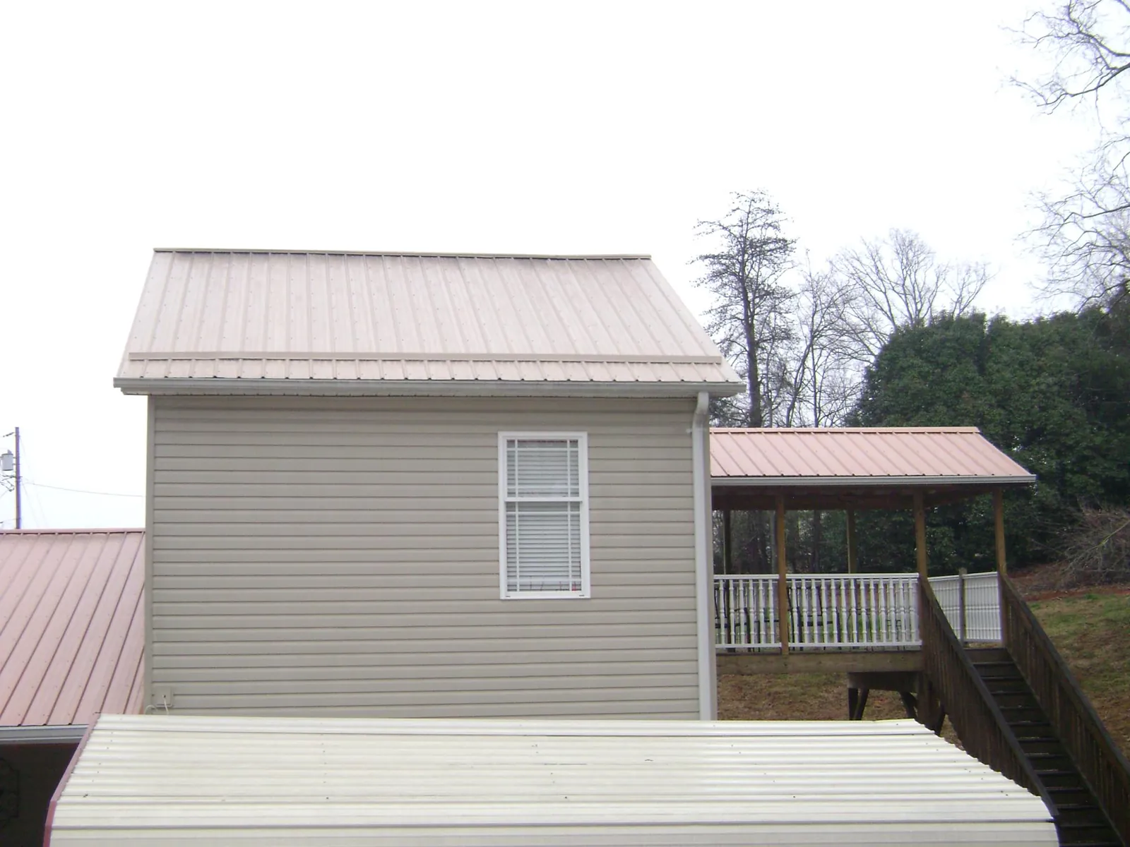 Tan metal roofs on a two story addition and attached porch, from a Roof Replacement job in Bybee