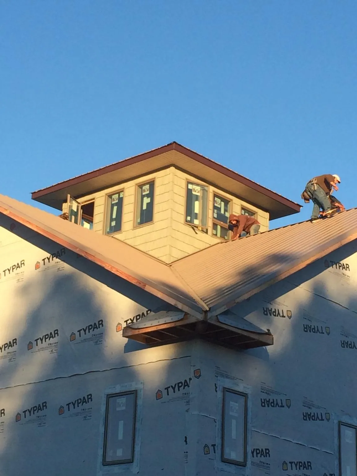 Roofers working around a rooftop cupola on a new metal roof at sunset — Roof Waterproofing in Bybee by Roofing Brothers